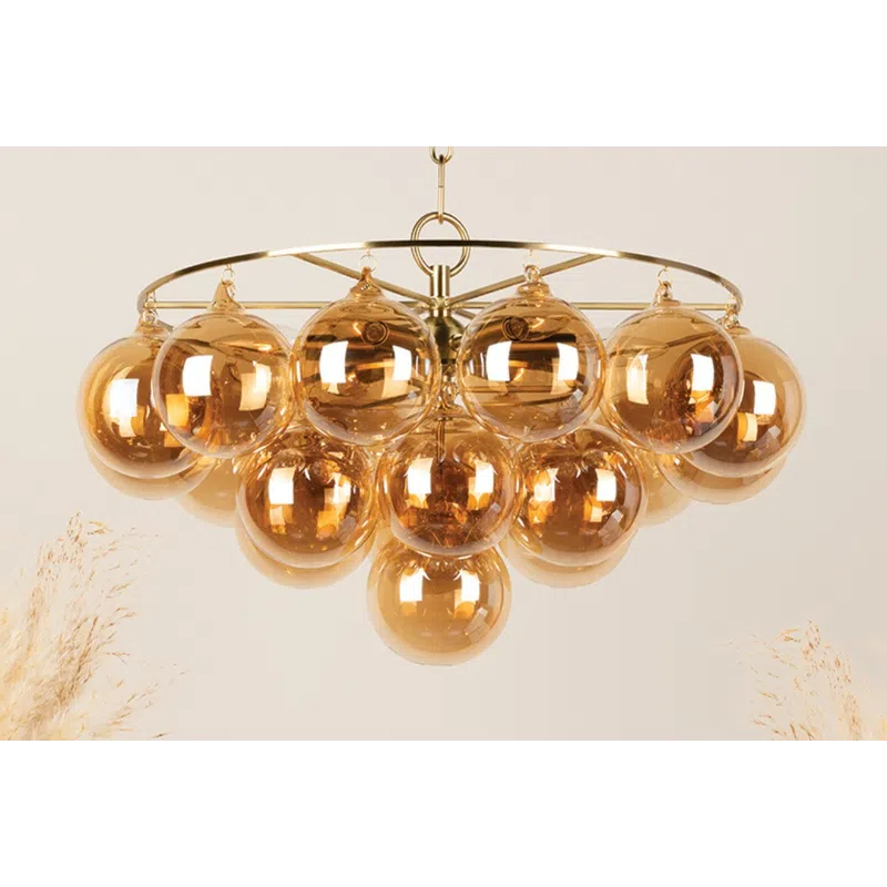 Modern chandelier with multiple amber glass globe bulbs hanging from a gold metal frame and chain.