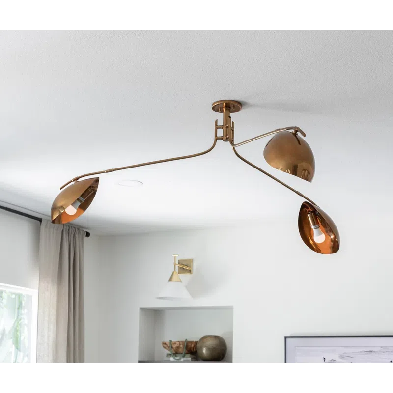 Modern living room with brass ceiling light fixture, built-in shelves, black floor lamp, and framed ocean photo.