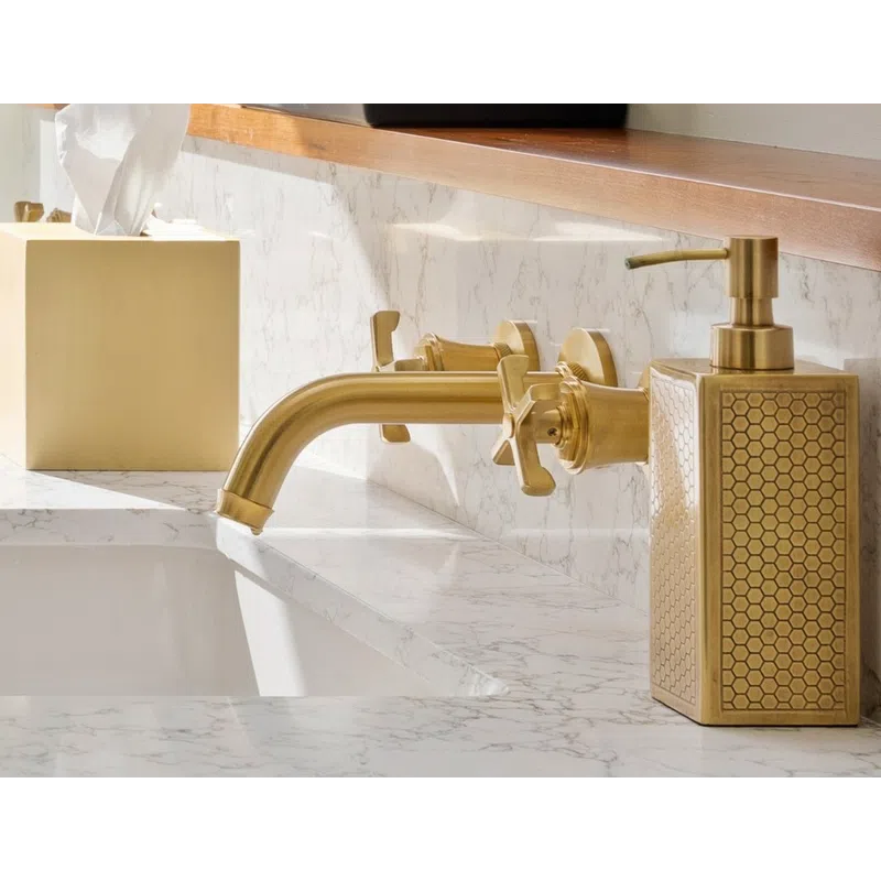 Modern bathroom sink with brass faucet, honeycomb patterned soap dispenser, and marble countertop.