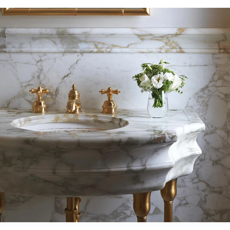 Elegant marble bathroom sink with gold fixtures and a small vase of white flowers on the countertop