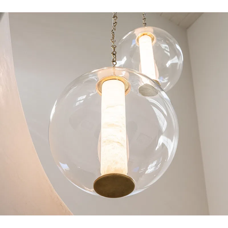 Three modern pendant lights with cylindrical white shades inside clear glass globes hanging from a white ceiling.