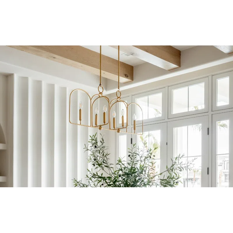 Bright modern dining room with wooden beams, white chairs, sculptural chandelier, and glass doors with greenery.