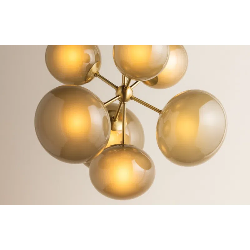 Modern chandelier with seven amber glass globes on brass arms hanging from ceiling.