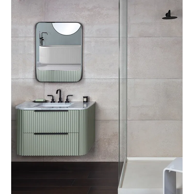 Modern bathroom with green vanity, black fixtures, glass shower enclosure, and white shower stool on dark floor.