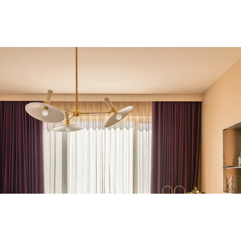Sunlit cozy bedroom with brown throw, colorful pillows, wooden round desk, decorative vase, and purple curtains.