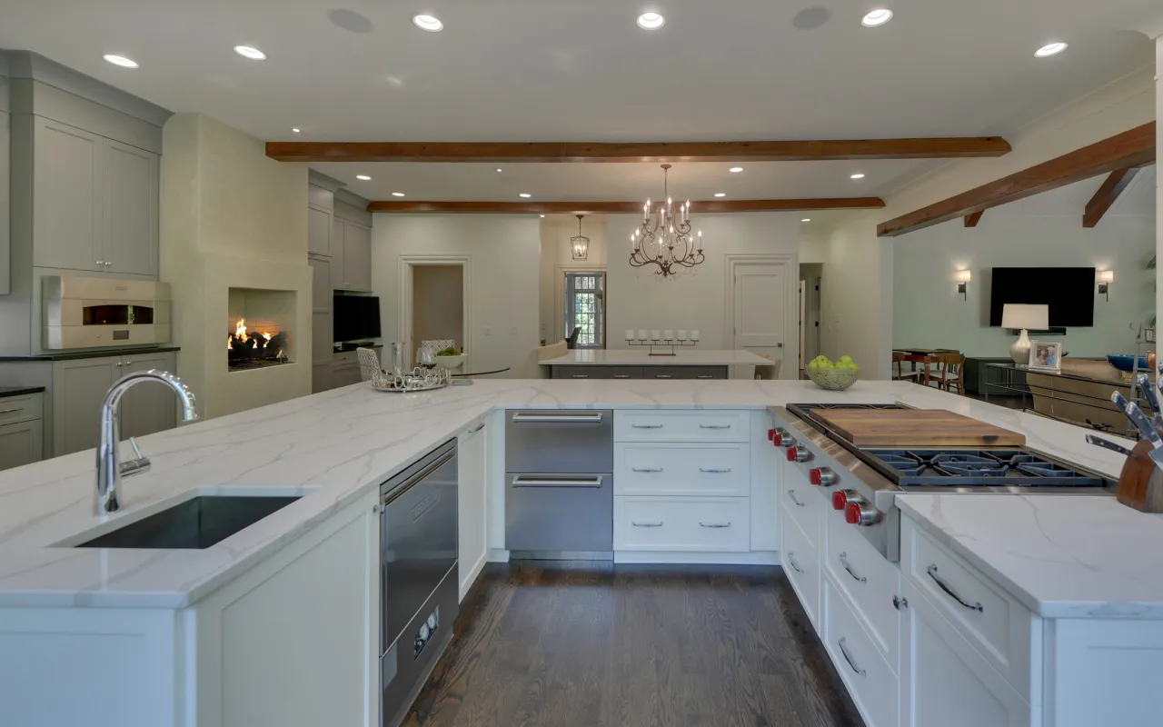 Modern kitchen with white marble countertops, stainless steel appliances, hardwood floors, and a built-in fireplace.