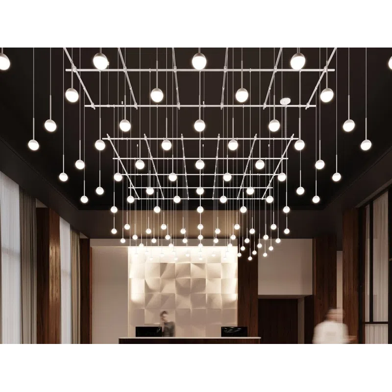 Modern office lobby with geometric wall design, hanging spherical lights, black curved sofas, and a wooden reception desk.