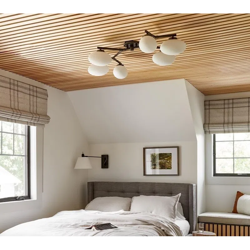 Cozy bedroom with wood slat ceiling, gray upholstered bed, neutral linens, striped rug, and natural light windows.
