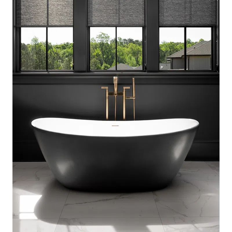 Modern black freestanding bathtub with gold faucet under windows showing green outdoor trees.