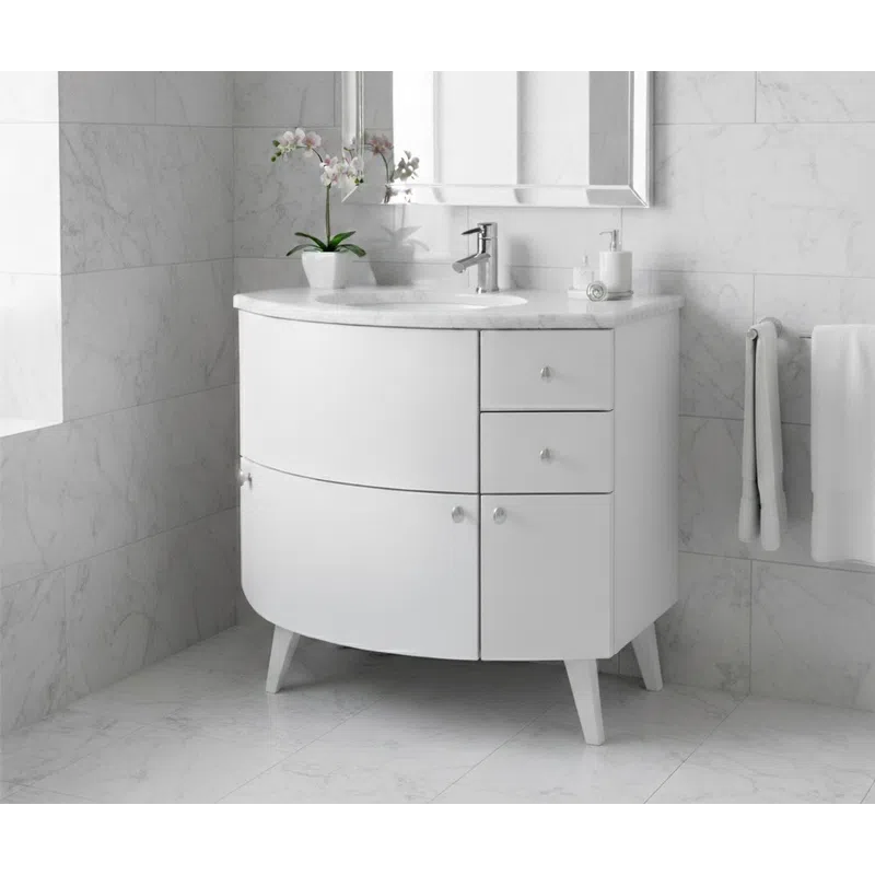 Modern white bathroom vanity with curved design, marble countertop, faucet, mirror, and orchid plant.