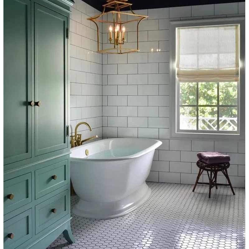 Elegant bathroom with white freestanding tub, green cabinet, hexagonal floor tiles, and gold chandelier under black ceiling.