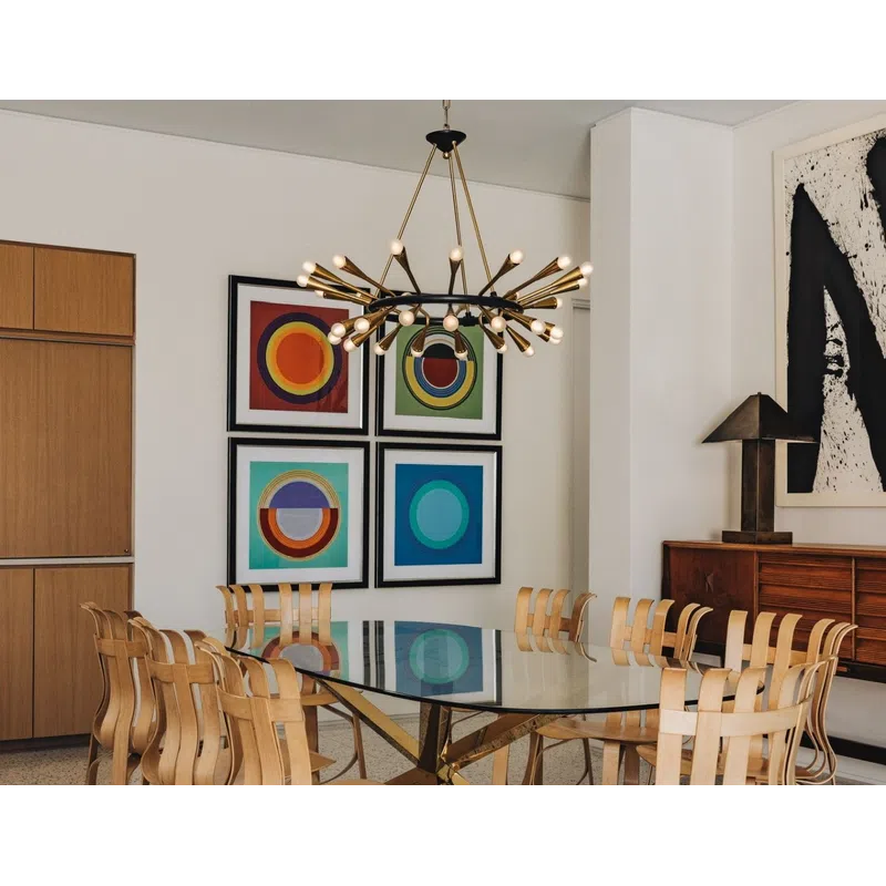 Modern dining room with glass table, unique wooden chairs, abstract wall art, and a contemporary chandelier.