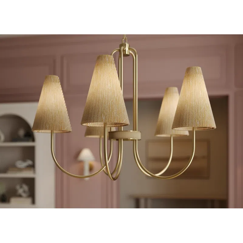 Elegant gold chandelier with fabric lampshades hanging over a floral centerpiece in a stylish pink-walled room