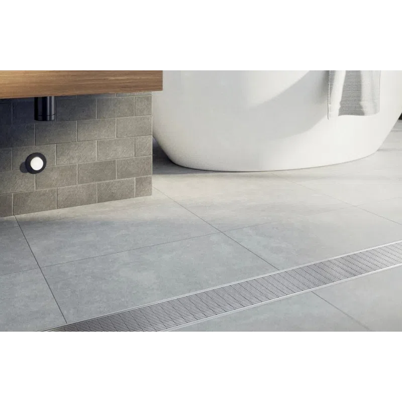 Modern bathroom with freestanding bathtub, gray tiles, wooden vanity, and metal floor drain cover.