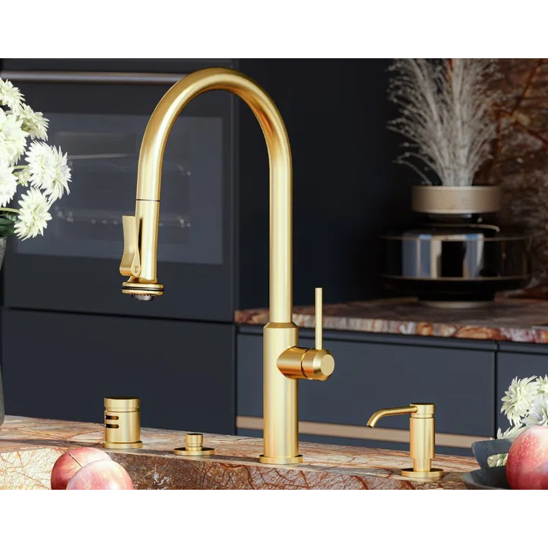 Modern kitchen sink with a gold faucet, marble countertop, and dark cabinetry accented by decorative plants.
