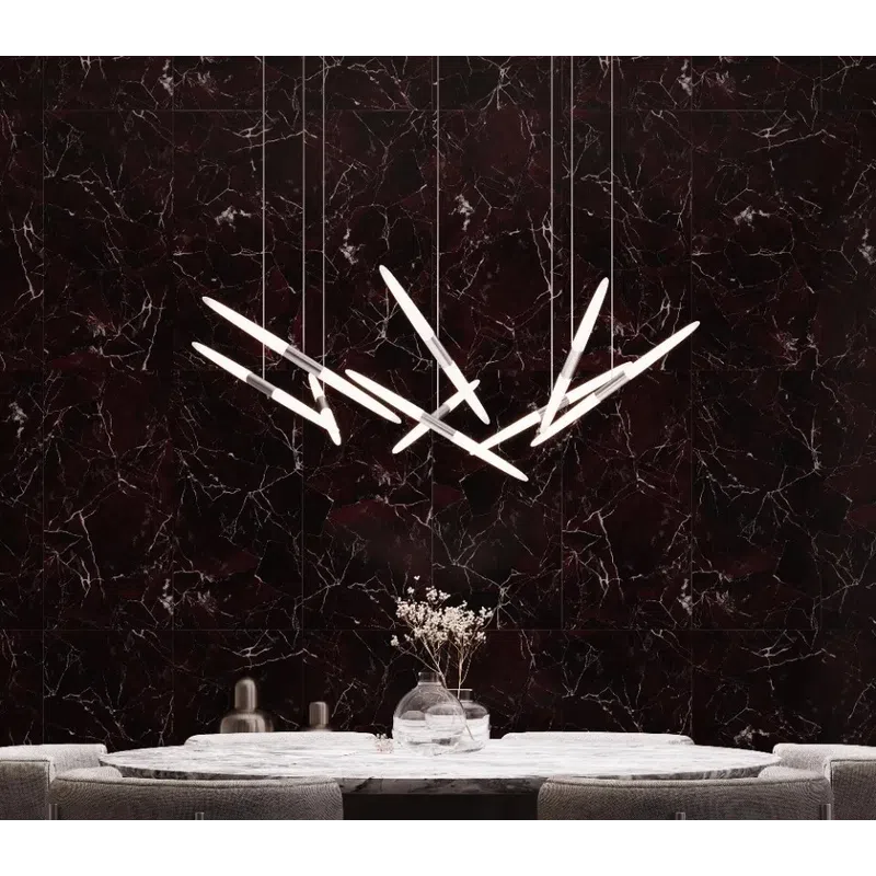 Modern dining room with round marble table, gray upholstered chairs, unique linear pendant lights, and dark marble wall.
