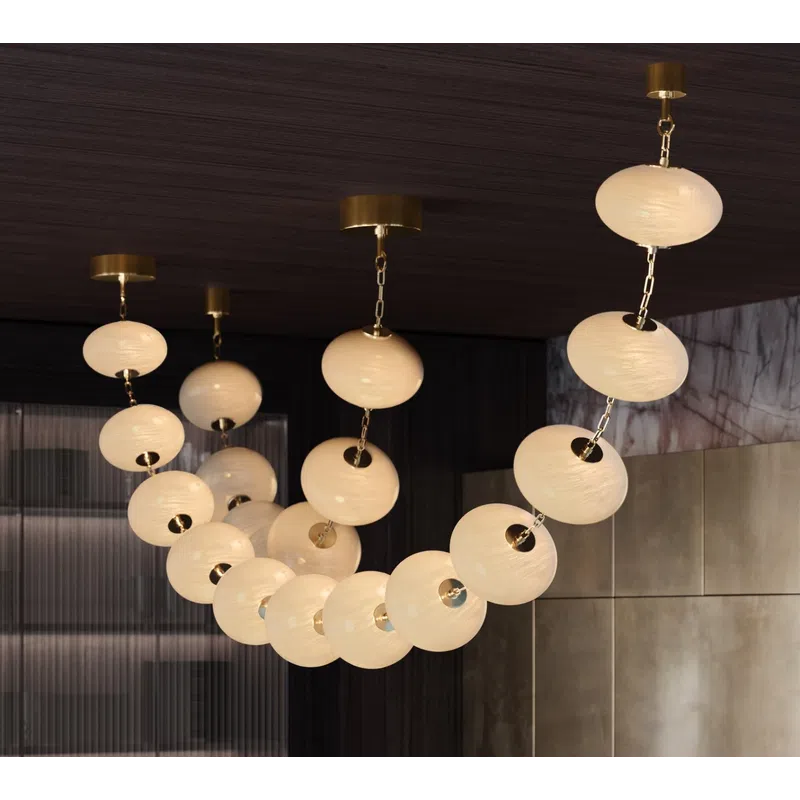 Modern chandelier with round, glowing white globes linked by gold chains in a stylish interior space.