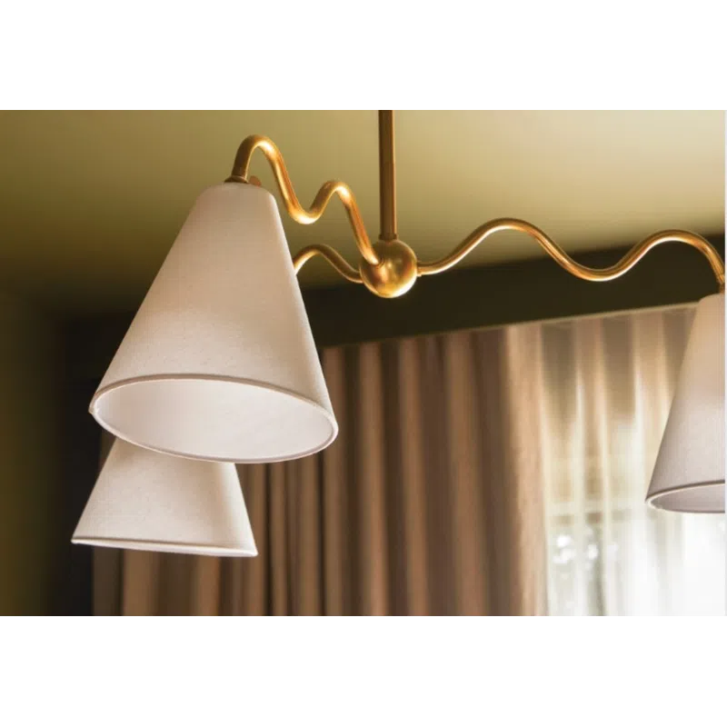 Modern ceiling light fixture with white cone-shaped shades and a wavy gold metal frame above beige curtains.