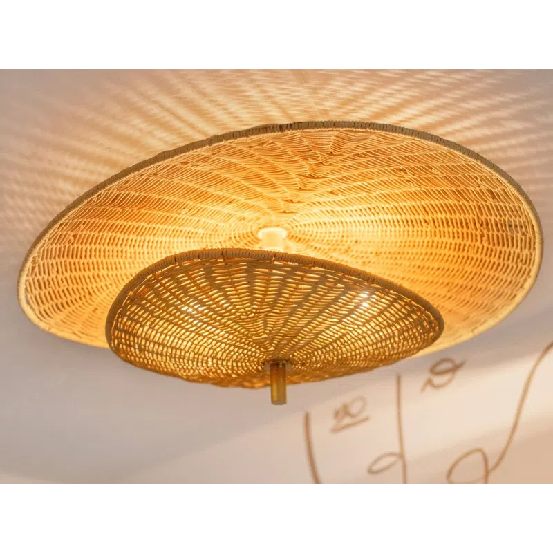 Woven rattan ceiling light casting patterned shadows on white ceiling with abstract face wall art.