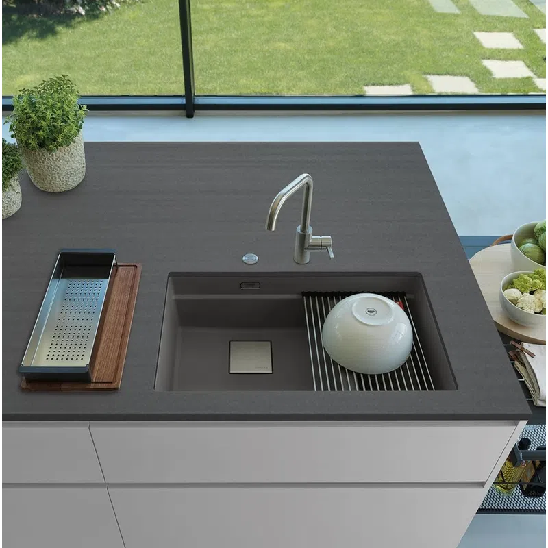 Modern kitchen sink with integrated drying rack on a sleek dark countertop beneath a window