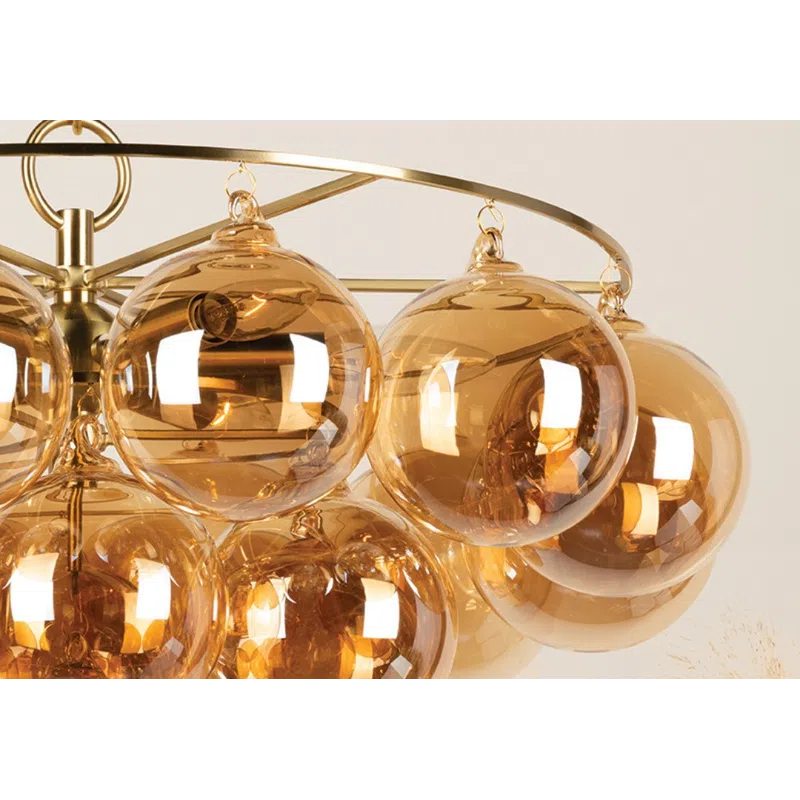 Modern chandelier with amber glass globe lights hanging from a gold metal frame against a neutral background.