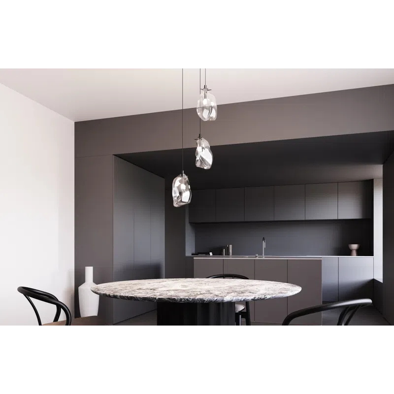 Modern dining space with round marble table, black chairs, and three pendant lights in a minimalist kitchen.