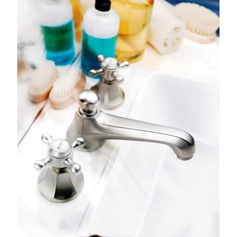 Close-up of a modern silver faucet with hot and cold handles on a clean white sink countertop.