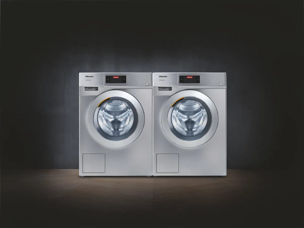 Two modern Miele washing machines displayed against a dark background for a sleek look.