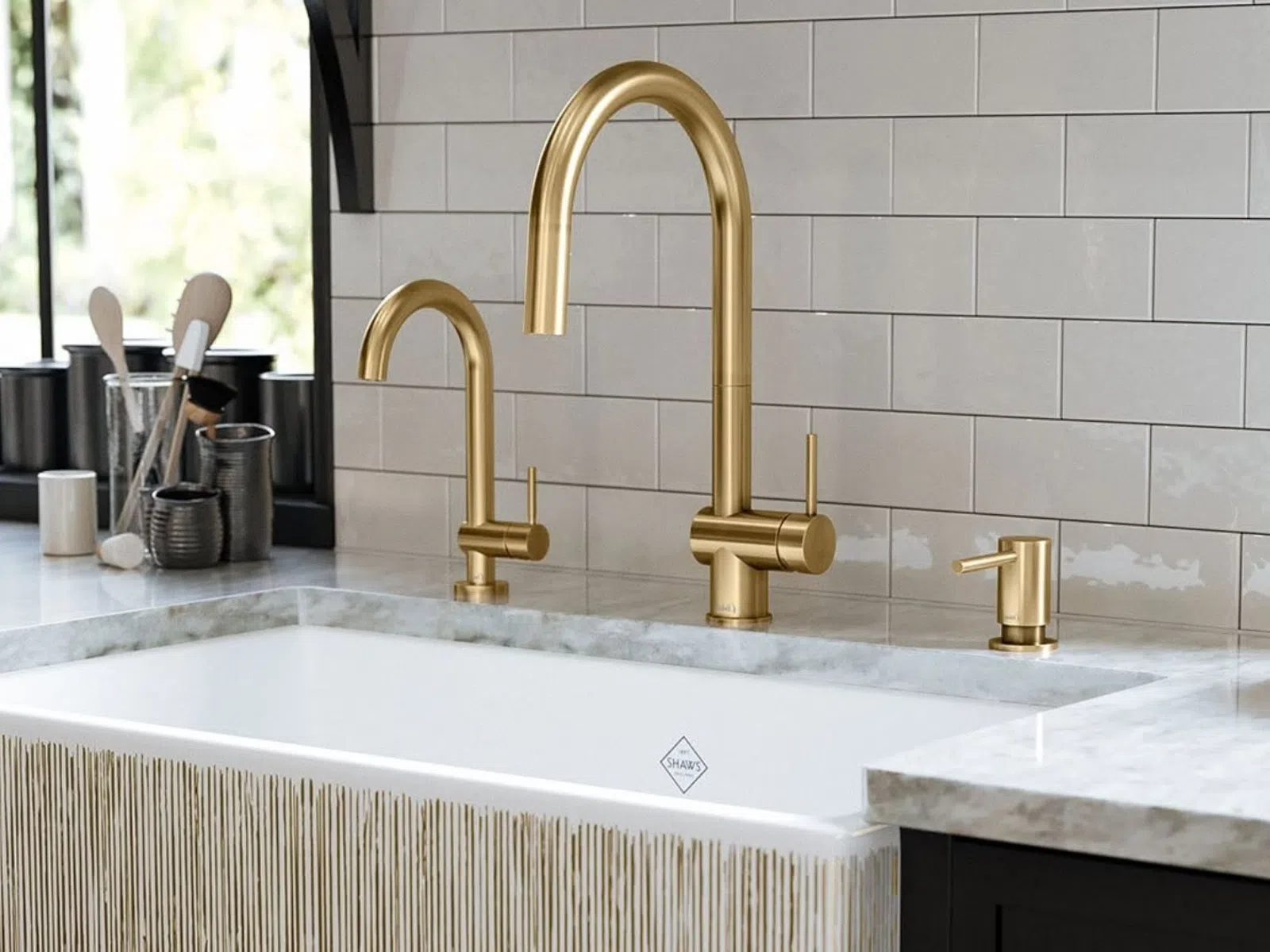 Modern kitchen sink with gold faucet, soap dispenser, and utensil holders on marble countertop