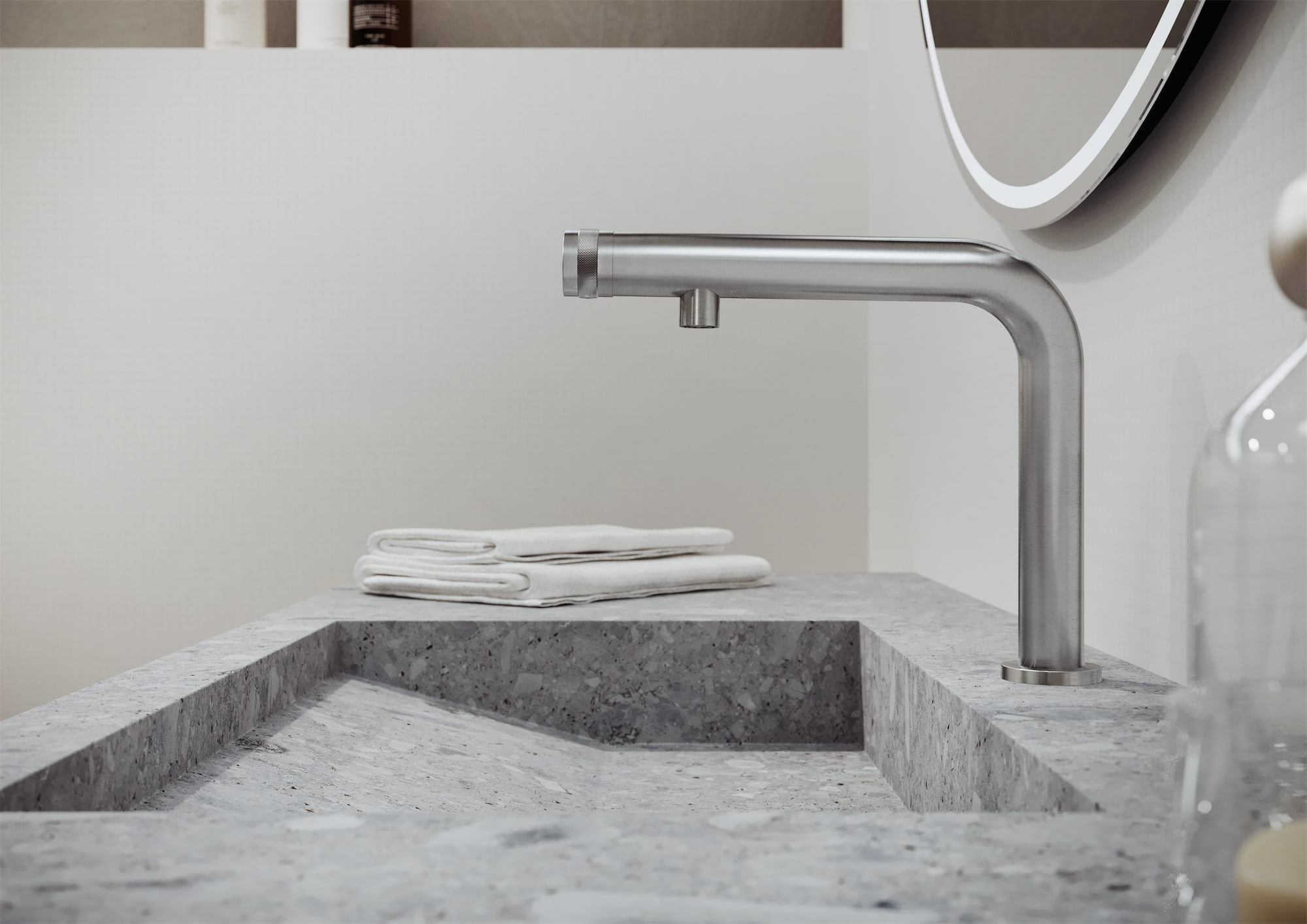 Modern bathroom sink with gray stone countertop, stainless steel faucet, and folded white towels on edge.