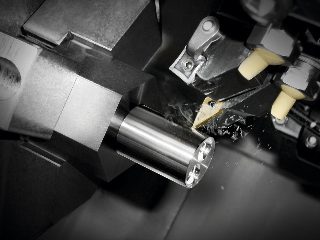 Close-up of CNC machine cutting metal cylindrical part with precision tool producing metal shavings.