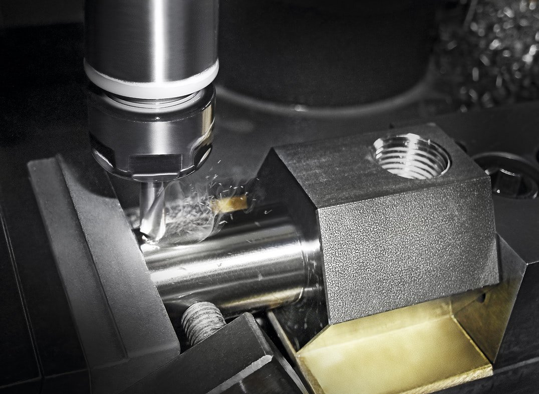 CNC machine milling a metal workpiece with sparks and coolant in an industrial workshop.