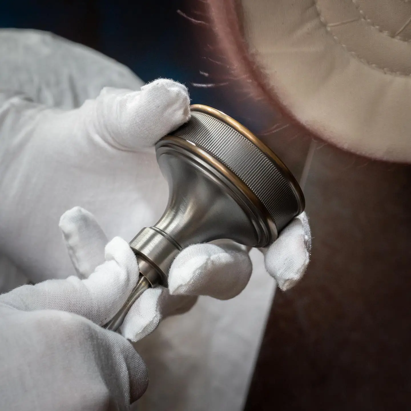 Craftsperson wearing white gloves hand-polishing a solid brass door knob.