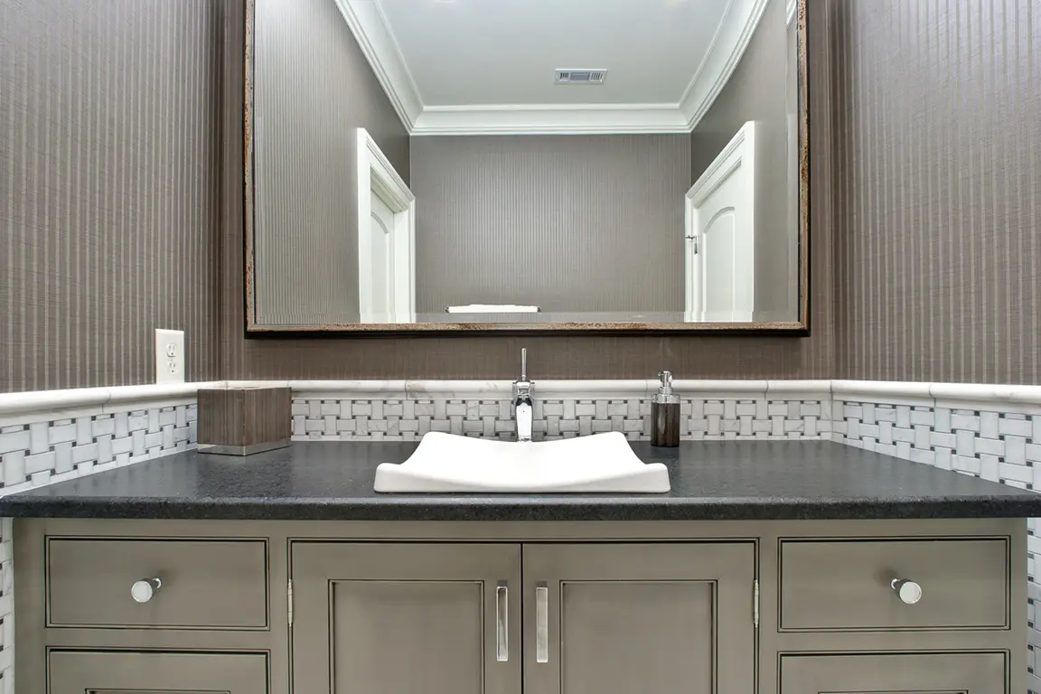 Modern bathroom vanity with a white vessel sink, gray countertop, large mirror, and patterned tile backsplash.