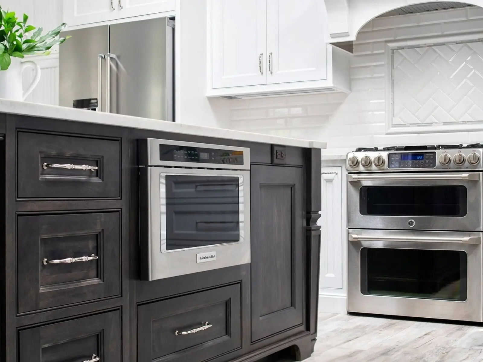 Modern kitchen with dark island, white cabinetry, and tiled backsplash