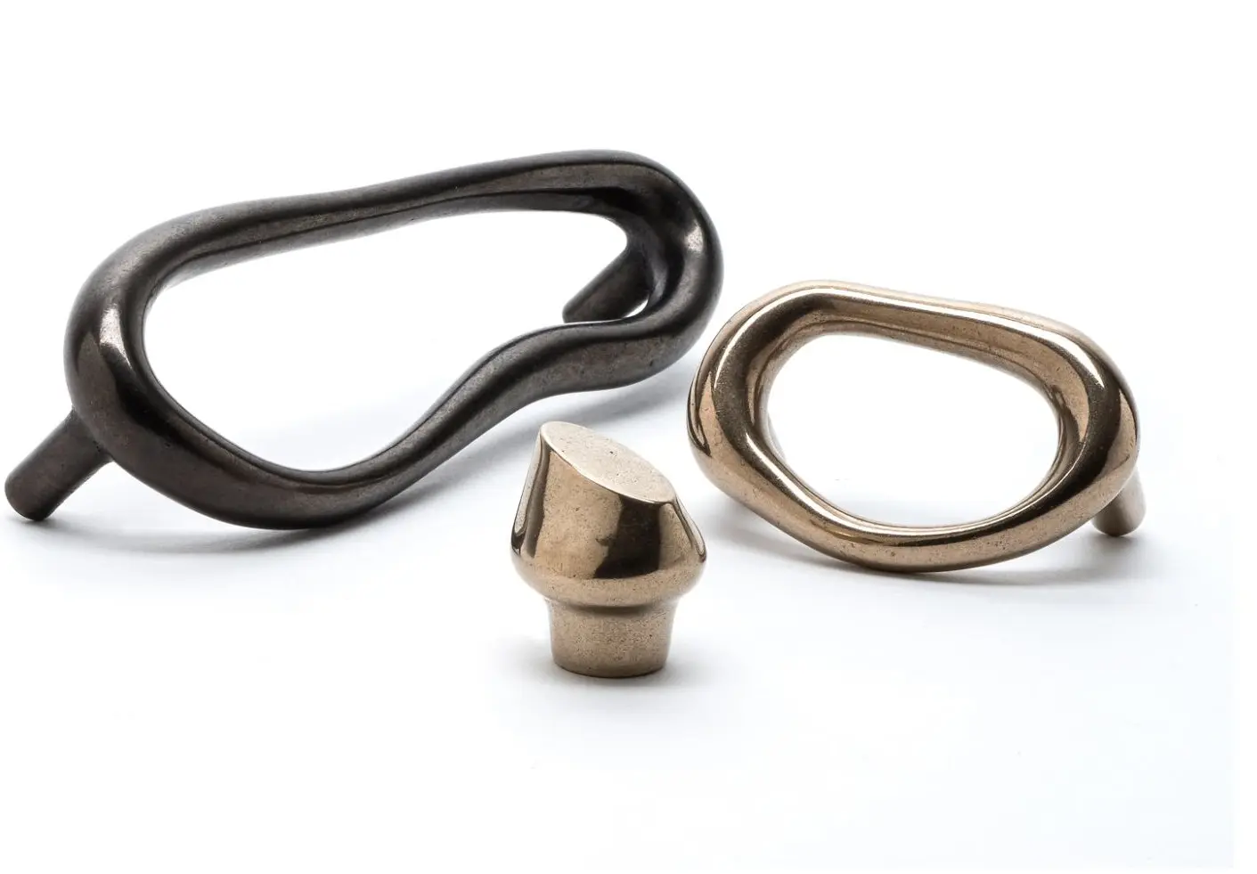 Sculptural cast bronze door pulls and a matching cabinet knob in dark and light bronze finishes on a white background.