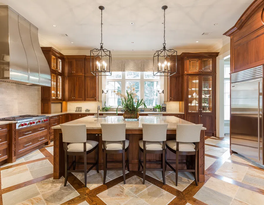 Spacious kitchen with wooden cabinets, stainless steel appliances, island with four chairs, and pendant lights.