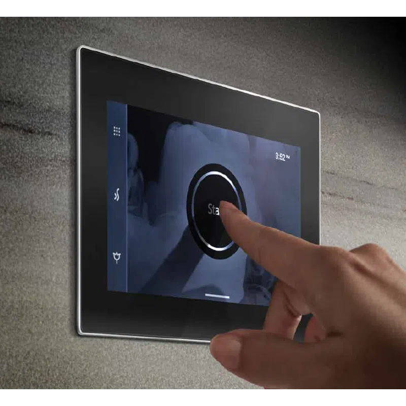 Hand pressing start button on a sleek wall-mounted touchscreen control panel with blue interface.