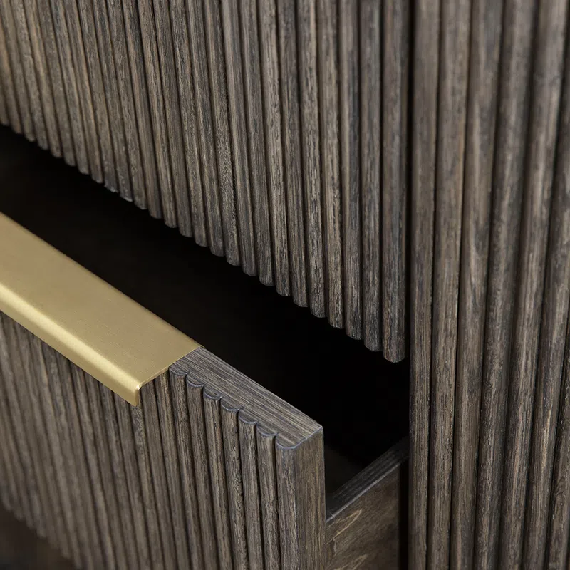 Close-up of a dark wood cabinet drawer with vertical grooves and a brushed gold handle partially open.