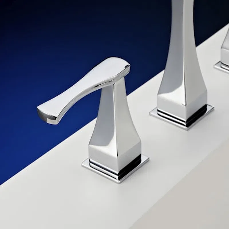 Modern chrome faucet handle with sleek geometric design on a white sink edge with deep blue background